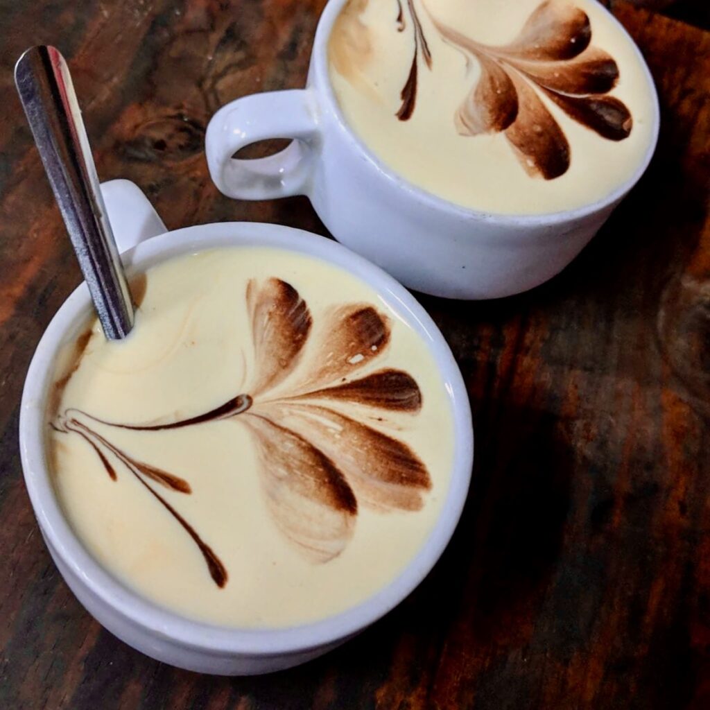 flower designs on top of two coffees with spoons