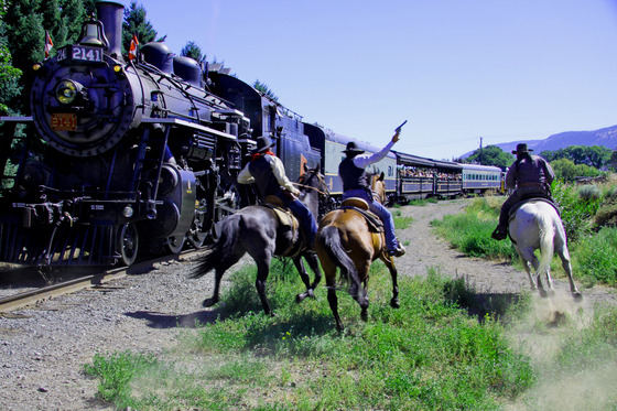 Train robbers on horseback (actors) firing pistols